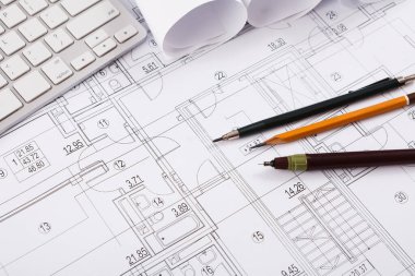 Bir tasarım planı koleksiyonu çalışma alanına yayıldı. Taslak kağıtların etrafına dolma kalem ve klavye gibi araçlar yerleştirilir. Dekor mimari veya tasarım için idealdir..