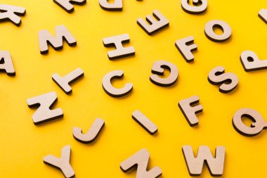 Farklı şekillerde ahşap harfler sarı bir yüzeye yayılır. Bazıları yüzlerini gösterirken diğerleri arkasını döner. Bu sahne, yaratıcılığın oluştuğu çalışma alanındaki bir anı yakalar..