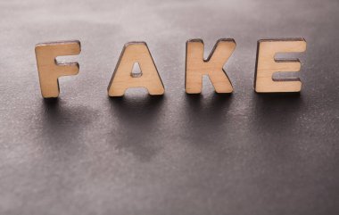 Dört ahşap harf karanlık bir yüzeye yerleştirilmiş sahte sözcüğü oluşturur. Harfler düzgünce düzenlenmiş ve açık renkli bir ahşaptan yapılmış. Arka planda belirgin bir kontrastı gösteriyor..