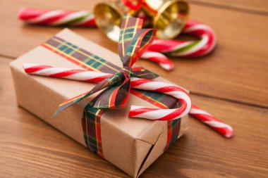 Noel eşyalarının bir koleksiyonu ahşap bir masanın üzerine konur. Bir hediye düz kağıda sarılır ve bir yayla bağlanır. Şeker kamışları ve çanlar, tatil sahnesine katkıda bulunmak üzere yakınlarda düzenlenmiştir..