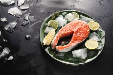 Bir somon filetosu buzla çevrili yeşil bir tabağa yerleştirilir. Balıkların yanında limon ve limon dilimleri var. Arka planda dağınık buz görünüyor. Taze deniz ürünleri kurulumunu gösteriyor..