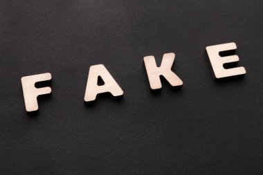 Sahte kelimesini oluşturmak için harfler düz bir yüzeye yerleştirilir. Harflerin metalik bir kaplaması var ve koyu arkaplanda göze çarpıyor..