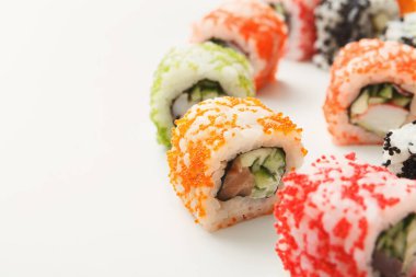 Farklı renklerde birkaç suşi rulosu beyaz bir tabağa yerleştirilir. Ekmekler çeşitli malzemelerle dolu. Bu sahne öğle yemeği saatinde bir Japon restoranını gösteriyor..