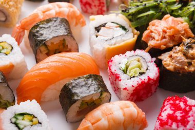 Bu kolaj, bazıları karides, somon ve sebzeli olmak üzere farklı suşi rulolarını içerir. Her parça beyaz bir yüzeye renkli bir görüntü için dikkatlice yerleştirilir..