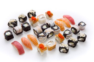 Çeşitli suşi parçaları beyaz bir yüzeyde düzgünce düzenlenir. Tabakta Nigiri, maki dürümleri ve farklı tatlar var. Parlak renkler ve farklı şekiller sergileniyor..