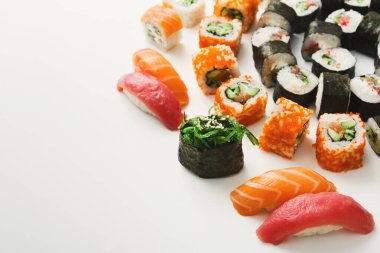 Suşi beyaz bir tabakta güzelce düzenlenir. Parlak turuncu somon ve yeşil yosun da dahil olmak üzere çeşitli ekmekler görülebilir..
