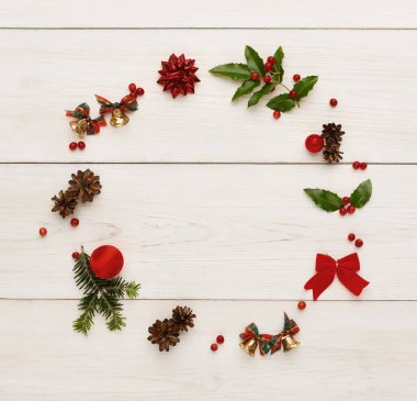 Tahta bir yüzeyde bir Noel süslemesi koleksiyonu düzenlenir. Kolajda çam kozalakları, kırmızı yaylar, böğürtlenler, çanlar ve mevsimlik bir görüntü oluşturan diğer şenlik öğeleri yer alıyor..