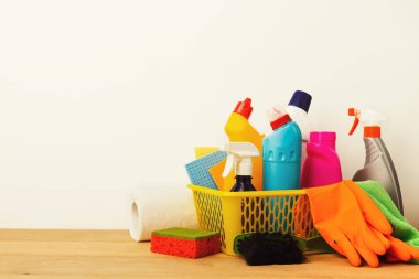 Tahta bir masada bir sepetin içinde temizlik malzemeleri sergileniyor. Koleksiyonda çeşitli temizlik işleri için şişe, sünger, eldiven ve havlular yer alıyor..