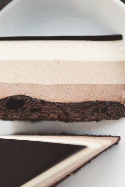 Tatlı katmanları yakın bir bakış açısında gösterilir. Tatlı, düzgün bir şekilde bitirilmiş çikolata ve krema katmanlarından oluşur. Katmanların dokusuna ve düzenine odaklanıyoruz..