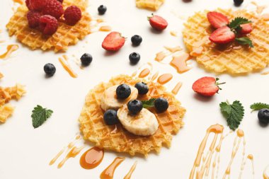 Waffle 'lar bir yüzeyde belli bir düzende sıralanır. Waffle 'lar çilek, yabanmersini, ahududu, muz ve şurupla kaplıdır. Nane yaprakları da garnitür olarak eklenir.