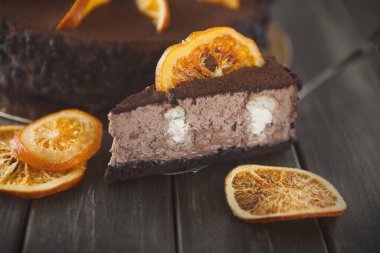 Farklı tatlılar ahşap bir masada birlikte düzenlenir. Odak noktamız çikolatalı turuncu pasta. Kurutulmuş portakal dilimleri pastanın üstüne oturur..