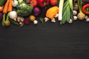 A collage displays a variety of fresh vegetables arranged on a dark wooden table. The selection includes carrots, tomatoes, broccoli, and mushrooms. This collection invites cooking and healthy eating.