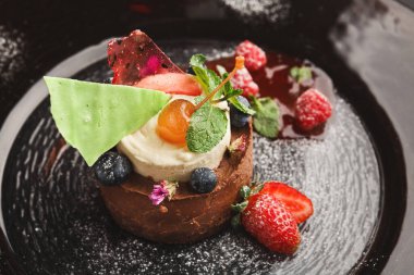 Kremalı ve taze meyveli çikolatalı pasta kolajı. Tabak, böğürtlen ve nane yapraklarından canlı renklere sahip. Bu lezzetli ziyafet görsel olarak çekici olacak şekilde tasarlandı..