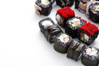 Suşi börekleri deniz ürünleri ve sebzeler de dahil olmak üzere farklı malzemeler sergiler. Çeşitli tipler farklı malzemelerle görülebilir. Sahne, suşinin temiz bir yüzeye düzgün yerleştirildiğini gösteriyor..