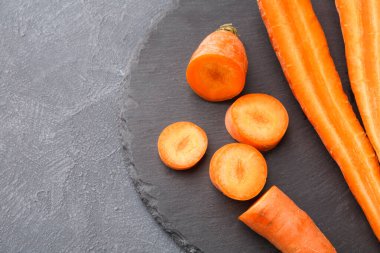 Havuçlar mermilere ayrılır ve koyu taştan bir yüzeyde bütün havuçların yanına serilir. Sebzeler taze ve yemek hazırlığı ya da atıştırma için hazır..