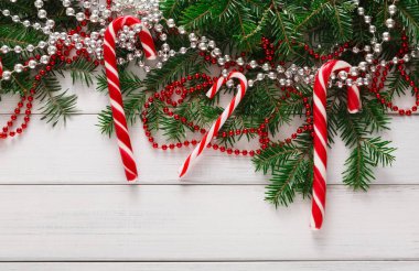 Şeker kamışları yeşil dallar ve parlak boncuklar arasında tahta bir masanın üzerine yerleştirilir. Dekor, tatil süslemeleri için ideal bir festival sahnesi gösteriyor. Kırmızı ve gümüş renkler göze çarpar.