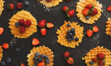 Koyu bir yüzeye yerleştirilmiş çilekli waffle, yaban mersini ve ahududu koleksiyonu. Bu set her waffle 'da çeşitli malzemeler gösteriyor. Tatlı seçeneklerinin eğlenceli bir gösterimi..