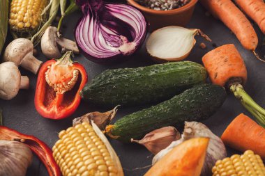 Bir kolajda salatalık, biber, soğan, mısır ve havuç gibi çeşitli taze sebzeler sergileniyor. Set renkli ve sağlıklı ürünleri pişirmeye veya sunuma hazır hale getiriyor.
