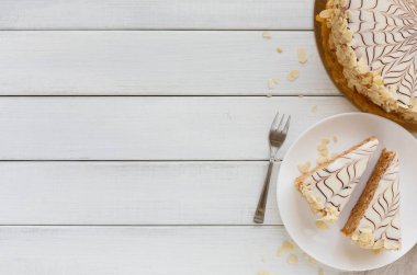 İçinde pasta dilimleri olan bir tabağın yanında tahta bir tahtanın üzerinde yuvarlak bir pasta bulunan bir kolaj. Tabağın yanında bir çatal duruyor. Kurulum açık ahşap bir masanın üzerine kurulmuş..
