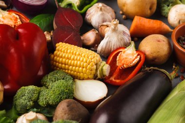 Çeşitli sebzeler kolaj tarzında bir araya getirilir. Düzenleme mısır, biber ve havuç gibi şeyleri içeriyor. Renkler ve şekiller karanlık bir yüzeyde çekici bir görsel ekran oluşturur..