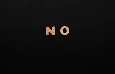 İki ahşap harf siyah bir yüzeye hayır diyor. Mektuplar süsleme ya da dikkat dağıtma olmadan yerleştiriliyor, metni açık ve okunması kolay hale getiriyor..