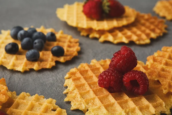 Waffle parçaları düz bir yüzeye rastgele dizilir. Çilek, yabanmersini ve ahududu gibi çeşitli meyveler waffle parçalarının üzerine konur..