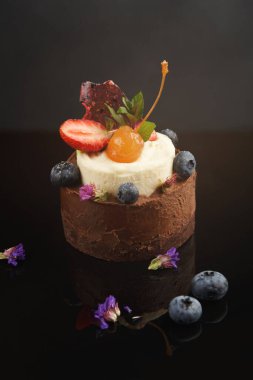 Bir tatlı kolajı koyu yüzeylerde sıralanmış meyveler ve yenilebilir garnitürlerle gösterilir. Her tatlı farklı malzemeler sunar. Çilek, yabanmersini ve çiçek gibi..