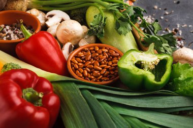 Bir yüzeyde taze sebze koleksiyonu düzenlenir. Kırmızı ve yeşil dolmalık biber, mantar, soğan ve fasulye mevcuttur. Bu set sağlıklı yemek ve yemek fikirlerini teşvik ediyor..