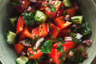 Bir kase taze otla karıştırılmış doğranmış domates, salatalık ve soğan koleksiyonu. Sebzeler parlak ve renkli. Sıcak bir gün için sağlıklı bir yemek seçeneği sunuyorlar..