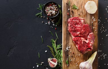 Çiğ sığır eti kesikleri ahşap bir kesim tahtasında düzenlenir. Etin etrafında sarımsaklı karanfil, taze otlar ve bir kase karışık biber ve tuz bulunuyor. Bu sahne bir mutfakta geçiyor..