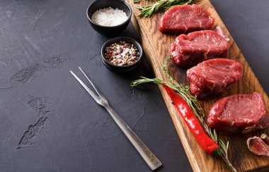 Tahtaya dört parça kırmızı et konur. Etin yanında küçük kaseler dolusu tuz ve karışık biber var. Bazı taze otlar ve kırmızı biber de mevcut..