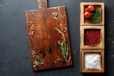 Taze otlar ve çeşitli baharatlar bir mutfaktaki ahşap kesme tahtasına güzelce yerleştirilir. Kırmızı domatesler de dahil. Ayarlar yemek hazırlığı öneriyor..