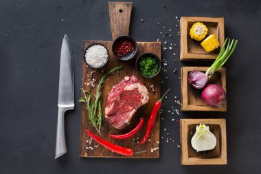 Çiğ et, taze sebzeler ve bitkilerle bir kesim tahtasına konur. Bir bıçak ve bir kase baharat düzgünce dizilir. Burası modern bir mutfak..