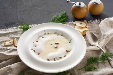 Masaya bir kase kremalı çorba konur. Çorba otlar ve baharatlarla süslenmiş. Ekmek dilimleri etrafa saçıldı. Masada tuzluk ve biberlik de var..