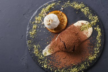 Tatlı tabağında bir kepçe vanilyalı dondurmanın yanında kakao tozuna bulanmış çikolatalı dondurma var..