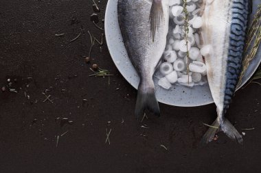 Balıklar buzla dolu bir tabakta düzenlenir. Sahne mutfak hazırlama bölümünü gösteriyor. İçindekiler yemek için hazır. Balıklarla çeşitli otlar da mevcuttur..