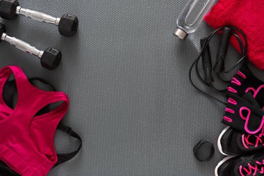 A workout space features dumbbells, a water bottle, a towel, and workout gear. The area is organized with a yoga mat as the base. The scene shows readiness for physical activity.