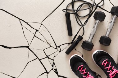 Pembe bağcıklı bir çift siyah atletik ayakkabı, kırık bir spor salonunda halat ve halatın yanındadır. Bu sahne spor malzemelerini spor salonunda gösteriyor..