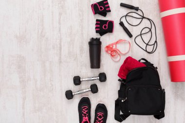 Workout gear is organized on the floor. A yoga mat, weights, a water bottle, and gloves are visible. Jump ropes and a bag are also included, ready for exercise.