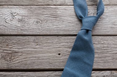 Mavi bir kravat tahıl desenlerini gösteren ahşap bir yüzeye düzgünce yerleştirilir. Arka planda sıcak bir ton var, bu da akşam ışığını gösteriyor. Ayarlar basit ve çok az detay içeriyor..