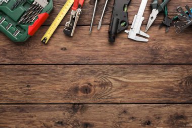 Aletler ahşap bir yüzeye düzgünce yerleştirilir. Matkaplı bir alet kutusu kerpeten, mezura ve kalibre gibi çeşitli el aletlerinin yanında gösterilir..