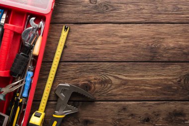Ahşap tezgahta bir alet çantası açık. Anahtarlar, pense ve mezura gibi birçok el aleti görülebilir. Ayar iyi aydınlatılmış ve onarımlar için uygun..