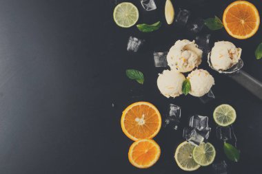 Üç kepçe dondurma, turuncu ve limon dilimleri ile çevrili karanlık bir yüzeye yerleştirilir. Buz küpleri ve nane yaprakları olay yerine yeni bir görünüm kazandırıyor..