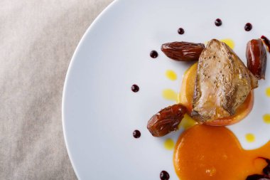 Tabakta sos, meyve ve hurma ile sanatsal olarak sıralanmış pişirilmiş bir et parçası yer alıyor. Bu tabak beyaz bir tabağa konmuş ve lokantalar için eşsiz bir aşçılık deneyimi sunmayı hedefliyor..