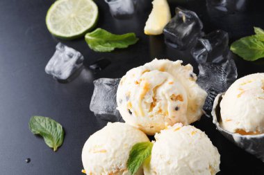 Üç kepçe dondurma nane yaprakları ve limon dilimlerinin yanına konur. Tatlıyı çevreleyen buz küpleri sıcak havalarda veya kutlamalarda tadını çıkarmaya hazır ferahlatıcı bir ziyafetin altını çiziyor..