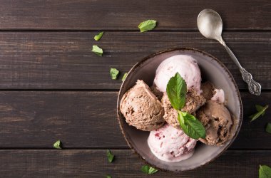 Üstünde taze nane yaprakları olan bir kasede bir sürü dondurma servis edilir. Ahşap masa bu yaz tatlısına kırsal bir dokunuş ekliyor, tatlı bir ikram sunuyor..