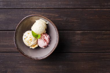 Bir kase ahşap bir masada elinde üç farklı dondurma kepçesi ile oturur. Kepçeler çeşitli tatlar. Bir nane yaprağı biraz renk katar. Ayarları basit ve davetkar..