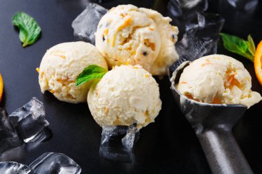 Yumuşak, kremalı dondurma kepçeleri buz küplerine konur. Portakal dilimleri ve nane yaprakları taze bir dokunuş ekler. Ayarlar lezzetli bir tatlı deneyimi için basit bir düzenleme gösteriyor..