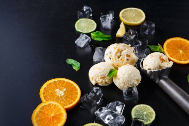 Üç kepçe dondurma portakal ve limon dilimlerinin arasında oturur. Buz küpleri etrafa saçılmış. Taze nane yaprakları mevcut. Bu sahne gündüz vakti siyah bir yüzeye kurulur..