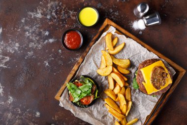 Peynirli bir hamburger, altın patates kızartması ve taze salatanın yanına oturur. Soslu iki küçük kase yemeği tamamlıyor. Keyif almaya hazır bir yemeği yakalamak sıradan bir şey..